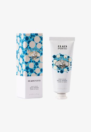 Handcrème in een witte tube met een klapdop naast een cilindervormige doos. De doos is versierd met blauwe stippen en een afbeelding van een schip. Beide zijn gelabeld met "Brise Marine."