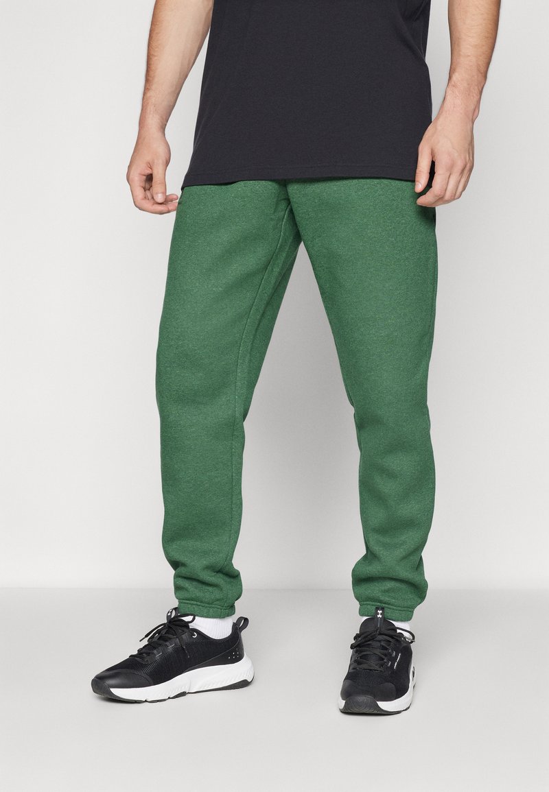 Grøn fleece sweatpants med en tapered pasform, elastisk talje og sidelommer, parret med sorte atletiske sneakers.