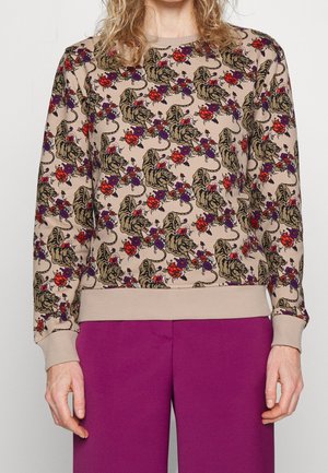 Béžová mikina s celoplošným vzorem tygrů a červených a fialových květin, doplněná živě fialovými kalhotami.