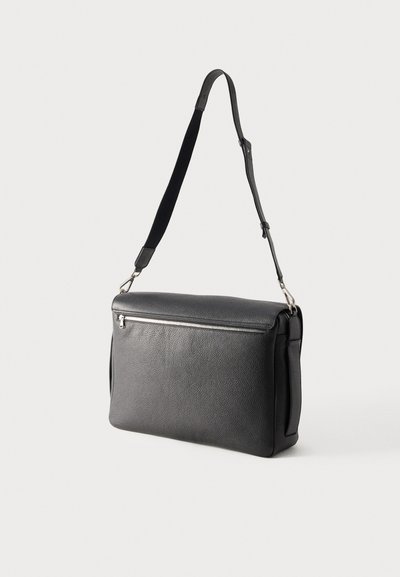 Črna teksturirana usnjena torba za čez ramo z nastavljivim trakom in horizontalnim žepom z zadrgo na sprednji strani.