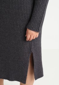 Ribbed knit dress in dark gray with metallic accents, featuring long sleeves and a side slit at the hem for added detail.