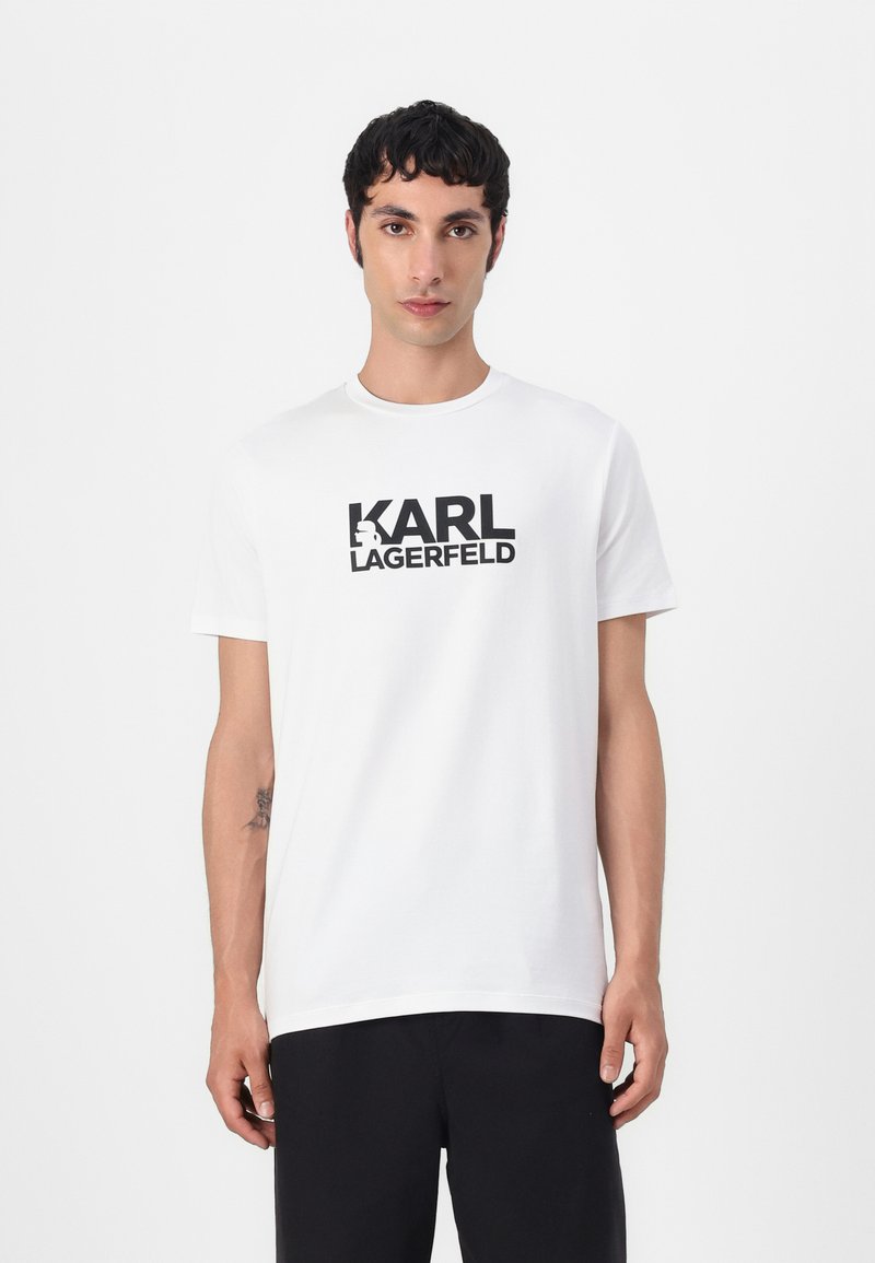 Hvit bomullst-skjorte med bold svart "KARL LAGERFELD"-tekst. Klassisk rund hals og korte ermer, jevn tekstur, avslappet passform.