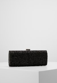Pochette noire texturée ; forme rectangulaire avec une surface perlée, dotée d'une fermeture métallique sur le dessus. Bords lisses et absence de motifs visibles.