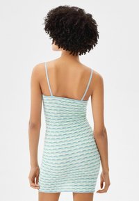 Robe bodycon avec un motif ondulé dans des teintes de vert et de bleu, dotée de fines bretelles et d'un tricot texturé. Design lisse et ajusté.