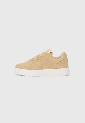 Beige suede sneaker met een gestructureerd oppervlak, ronde neus en witte rubberen zool. Kenmerkt zich door platte veters en subtiele zijnaaddetails.