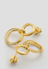 Orecchini in metallo color oro con forme ovali allungate interconnesse, uno decorato con una fila di cristalli trasparenti lungo il bordo.