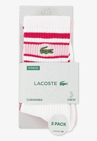 Κάλτσες τύπου crew σε πακέτο των 3, με λευκές και ροζ οριζόντιες ρίγες. Περιλαμβάνουν πράσινο λογότυπο κροκοδείλου Lacoste και μαξιλαρωτό σχεδιασμό.
