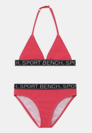 Costume da bagno rosa con un top triangolare a spalline sottili e un fondo coordinato. Entrambi i pezzi hanno un elastico nero con il testo "SPORT BENCH".