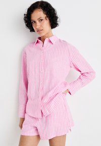 Rosa og hvitstripet knappskjorte med lange ermer, kombinert med matchende stripete shorts. Laget av bomull med et avslappet design.