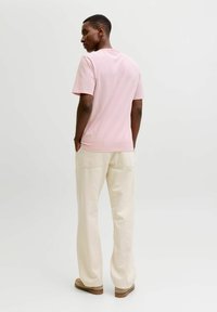 Hellrosa kurzärmeliges T-Shirt mit lockerem Schnitt, kombiniert mit cremefarbenen, weitem Hosen mit Gesäßtaschen und weicher Textur.