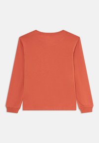Långärmad T-shirt i dämpad orange. Tillverkad av mjuk bomull, med en enkel rund halsringning och åtsittande ärmar. Enfärgad utan mönster.