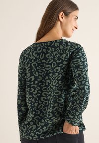 Maglietta a maniche lunghe con stampa leopardata verde, realizzata in un tessuto morbido, con scollatura rotonda e vestibilità comoda, dotata di una cucitura visibile sul retro.