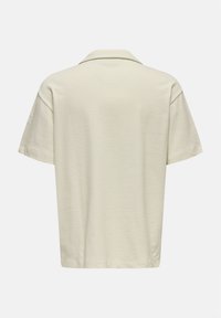 Polo a maniche corte in tessuto beige chiaro, con colletto classico e una vestibilità rilassata, caratterizzato da una trama sottile e dettagli di design minimal.