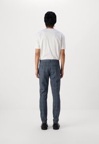 Eng anliegende blaue karierte Hose aus strukturierter Stoff, mit Gürtelschlaufen, zwei Gesäßtaschen und schmal zulaufenden Beinen, kombiniert mit einem weißen T-Shirt.