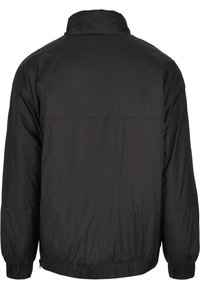 Black, oversized jacket with a high collar, elastic cuffs, and a cinched hem, crafted from lightweight, shiny material. Simple design, no visible logos.