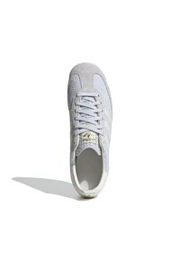 Light gray sneaker with mesh upper and suede toe cap, featuring white stripes and gold logo on tongue. Rounded toe and flat sole.