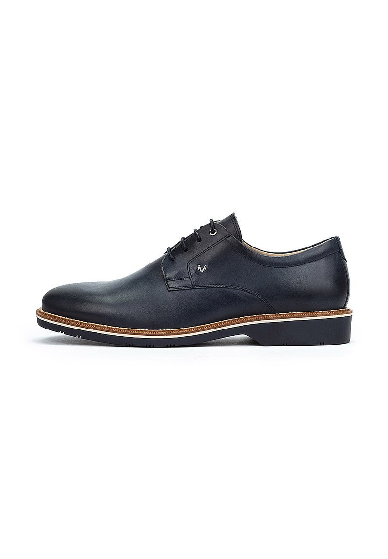 Chaussure habillée en cuir noir avec une finition lisse, design à lacets et couture de semelle en tan. Bout arrondi et semelle en caoutchouc texturée basse.