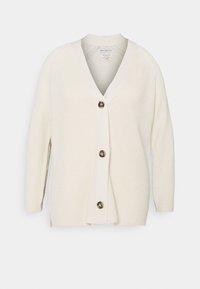 Cardigan color crema con scollo a V, texture a coste e grandi bottoni marroni sul davanti. Presenta maniche lunghe e una vestibilità comoda.