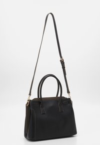 Svart läderhandväska med justerbar axelrem, rundade handtag och detaljer i guldmetall. Har kontrasterande färgstickningar och sidopaneler.
