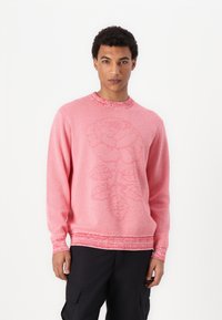 Genser med rund hals i lys rosa, med en teksturert rose-design. Ribbestrikket hals og mansjetter med kontrasterende detaljer nederst.