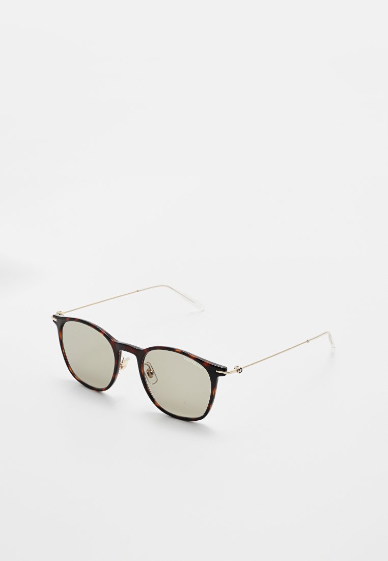 Occhiali da sole rotondi con montatura in tartaruga, lenti verdi e sottili bracci in metallo dorato. La montatura presenta un design classico con dettagli sottili.
