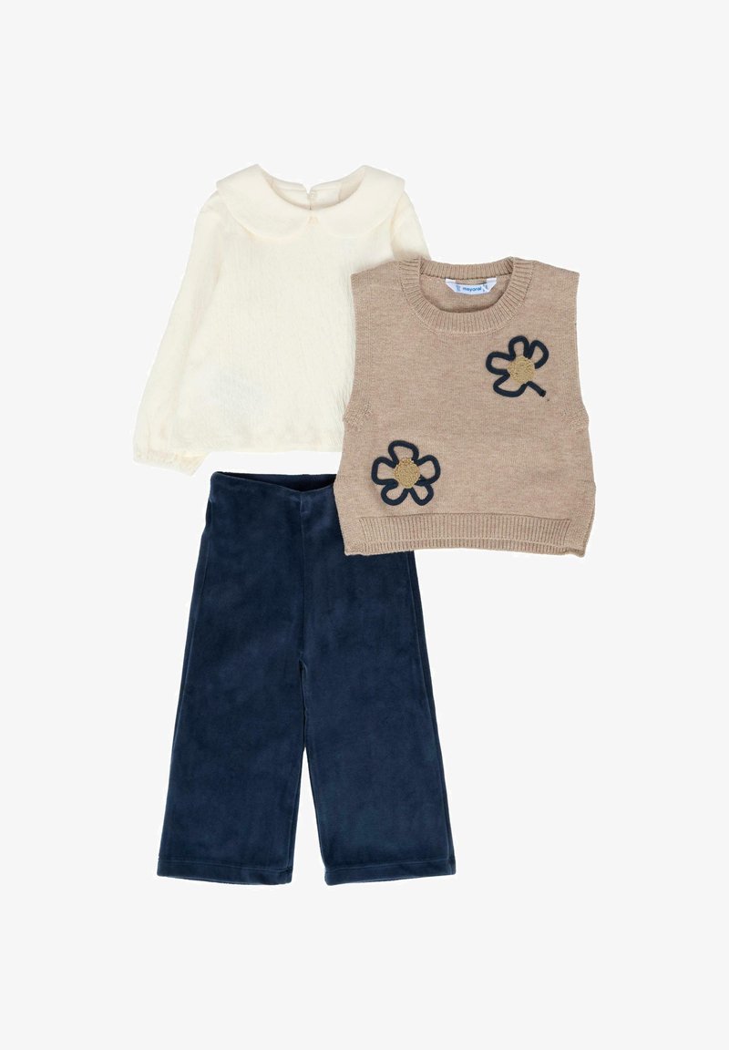 Maglione senza maniche in maglia beige con dettaglio floreale, camicetta a maniche lunghe crema con colletto, e pantaloni larghi blu navy. Texture morbide.