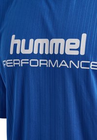 Blå sportskjorta i texturerad tyg med vertikalt randmönster. Stort vitt "hummel"-logotyp och "PERFORMANCE"-text.