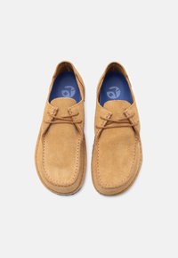 Ταμπά παπούτσια από σουέντ με στρογγυλεμένη μύτη, διακοσμημένα με ραμμένη επένδυση και κορδόνια. Το εσωτερικό διαθέτει μπλε διάτρητη εσωτερική σόλα.