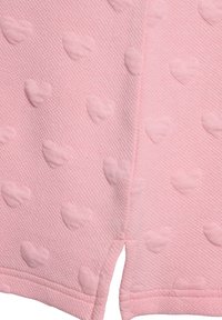 Tissu rose avec un motif de cœurs texturés, présentant de subtiles formes de cœurs en relief. Le matériau a une apparence côtelée et un bord net et fini.