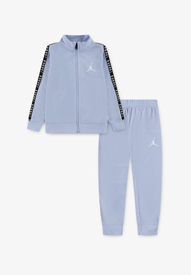 Completo giacca e pantaloni azzurro chiaro, realizzato in tessuto morbido. La giacca presenta strisce laterali nere e un logo bianco; i pantaloni hanno una vita elasticizzata.