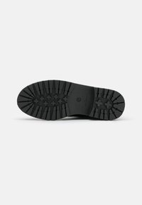 Suela de zapato de goma negra con un patrón de relieve que presenta formas de cruz elevadas y ranuras para mayor agarre. Textura lisa con bordes redondeados.