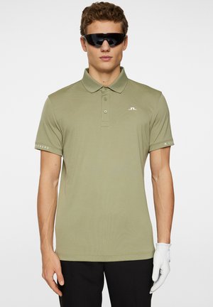 Olive green polo shirt with a collar, short sleeves, and front buttons. Features a small logo on the chest and text detail on the sleeve.