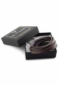 Brown leather bracelet in a black box lined with gray. Features braided texture and smooth sections, presented with a logo on the lid.