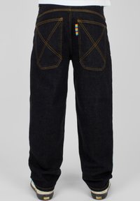 Mørke denimjeans med en avslappet passform, med kontrasterende gul søm, dekorative baklommer og en flerfarget etikett bak.