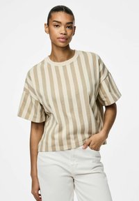 T-shirt a righe beige con una vestibilità comoda e maniche corte, realizzato in morbido cotone. Abbinato a pantaloni chiari.