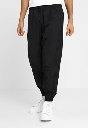Black jogger pants with an elastic waistband and side stripes. Made from lightweight fabric, featuring cuffed ankles and side pockets.