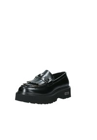 Mocasines de cuero negro con diseño de flecos y acentos de tachuelas en forma de pirámide. Suela de goma gruesa y texturizada que proporciona mayor altura y estabilidad.