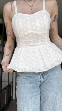 Bílý peplum top s krajkovou výšivkou, nastavitelnými ramínky a strukturovanou tkaninou. V kombinaci se světle modrými džíny.