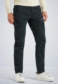 Schwarze Cargo-Hosen mit mehreren Taschen, aus einem leichten, strapazierfähigen Stoff mit glatter Textur. Kombiniert mit weißen Sneakern.