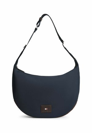 Navy blue crescent-shaped shoulder bag with adjustable strap and a small rectangular logo patch centered at the bottom front.
