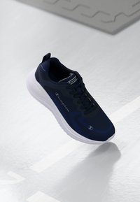 Navy athletic shoe with a smooth synthetic upper, white textured sole, lacing system, and "Champion" logo on the side.