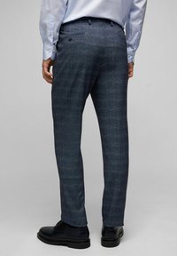 Marineblaue maßgeschneiderte Hose aus strukturiertem Stoff. Verfügt über eine flache Vorderseite, Gesäßtaschen und ein schlankes Design. Kombiniert mit schwarzen Schuhen.