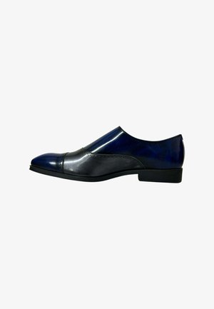 Zapato formal de hombre tipo slip-on en cuero negro brillante y azul oscuro con tacón bajo y perforaciones decorativas en la puntera y los laterales.