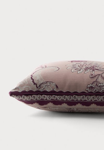 Coussin rectangulaire doux avec des motifs floraux violets et cachemire et bordure décorative en feston sur fond clair.