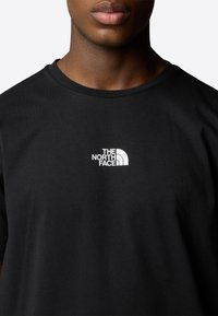 Black cotton t-shirt featuring a white logo of "The North Face" centered on the chest, with a crew neck and short sleeves.