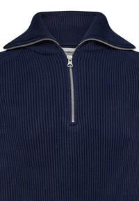 Pull-over côtelé bleu marine avec col montant et détail de fermeture éclair argentée. La texture est finement tricotée, offrant chaleur et confort.