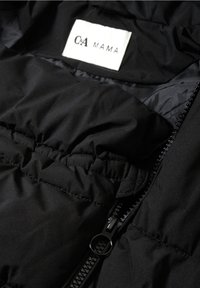 Chaqueta acolchada negra con cremallera brillante y detalles elásticos. La etiqueta muestra la marca "C&A MAMA". El material parece suave y liso.