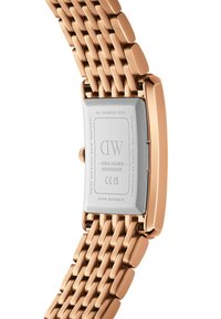 Stainless steel watch with a rose gold mesh strap and rectangular silver case. Features engravings on the back, including a serial number.