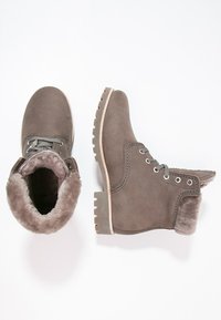 Bocanci gri din suede cu căptușeală din blană artificială, vârf rotund, șireturi în față și talpă din cauciuc texturat. Dispune de ochiuri din metal și o bandă de tragere pe spate.