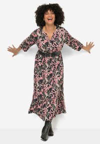 Robe maxi avec un imprimé animal rose et noir, décolleté en V, manches 3/4 et un ourlet volanté, cintrée à la taille avec une ceinture noire cloutée.